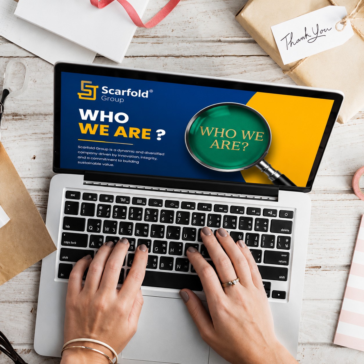 A laptop showing the Scarfold Group &ldquo;Who we are&rdquo; slide.
